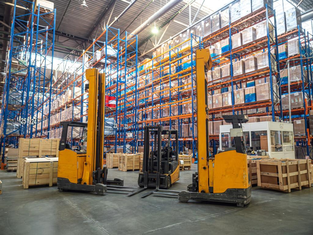 Several forklifts by high shelves, stacked with boxes