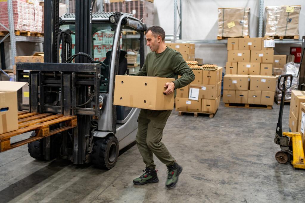 Man working at warehouse, carrying cardboard box